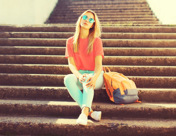 夏天的肖像时髦的金发女郎背双肩包，墨镜在城市图片下载