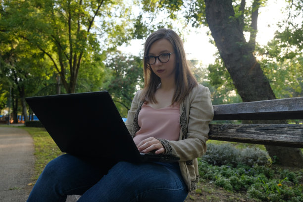 年轻女子在公园里用笔记本电脑工作图片下载