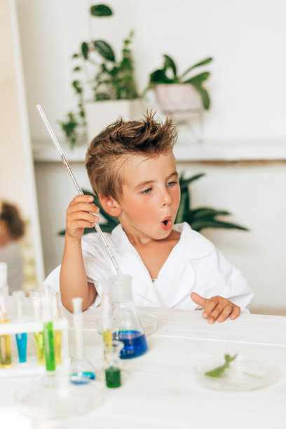 穿着白色制服的好奇小男孩在实验室里做化学实验。回到学校概念。年轻的科学家。自然科学。儿童学前及学校教育图片下载