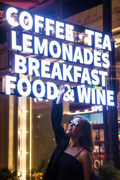 肖像积极的女人在墨镜跳舞的夜晚城市霓虹灯的背景。剪影年轻时髦的女性抬头看夜街。夜生活青年氛围概念。复制文本空间图片下载