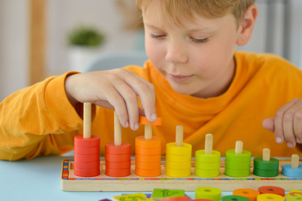 儿童数学游戏。男孩玩五颜六色的戒指。天然材料,木质。分数,数字组成。家庭教育理念，早期发展，技能。图片下载