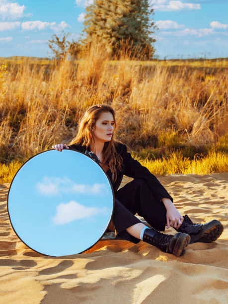 秋天的早晨，一个金发女郎坐在沙滩上。图片下载