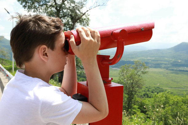 男孩用双筒望远镜观察Azish-Tau山脊图片下载
