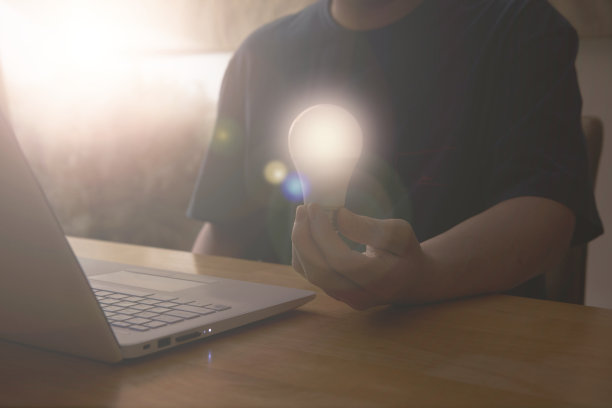 手持灯泡图形，同时使用笔记本电脑在理念创新动力为解决方案和技术经营理念图片下载