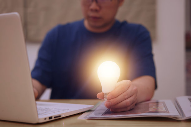 人类以灯泡的创意和想象力运用笔记本电脑的创新技术和解决概念图片下载