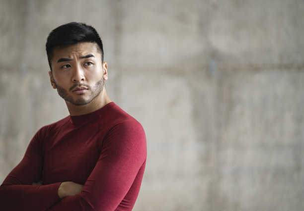 英俊的亚洲年轻男子穿着运动服，复制空间与墙壁背景素材图片