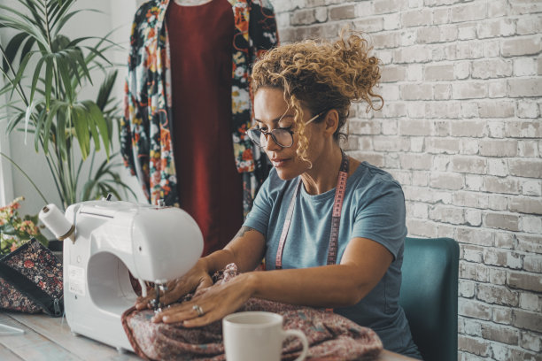 缝纫女工:在家里或车间使用或使用缝纫机工作的女工快乐的工作女性与家庭替代商业生活方式的概念。设计师做衣服的爱好图片下载
