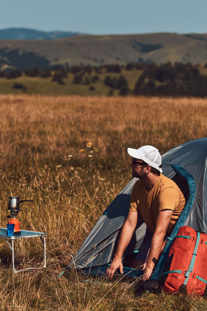 男人在大自然中露营，在户外拆行李和打包小帐篷，娱乐和爱好。图片下载