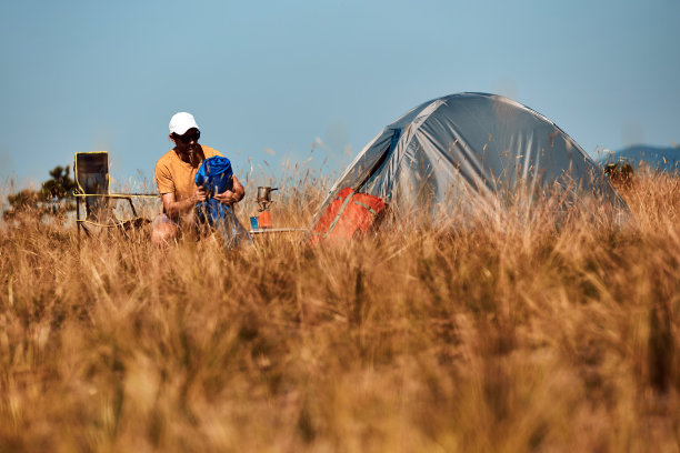 男人在大自然中露营，在户外拆行李和打包小帐篷，娱乐和爱好。图片下载