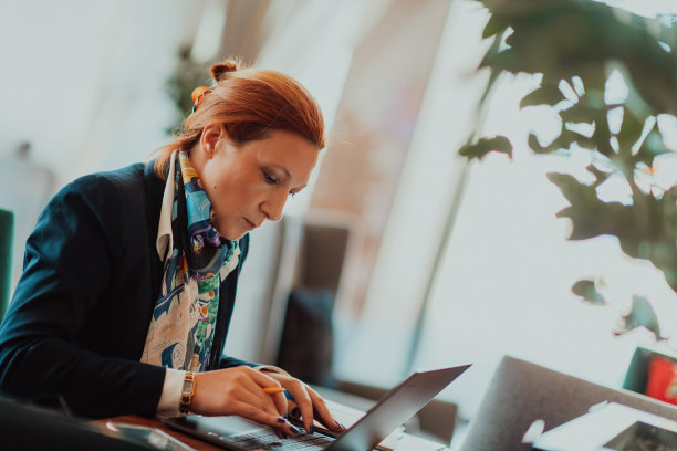 一位老妇人坐在现代公司里用笔记本电脑进行商业项目和任务的照片图片下载