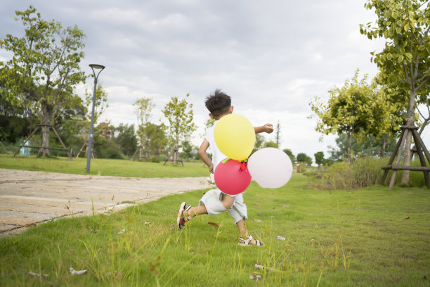 亚洲小男孩在草地上玩气球图片下载