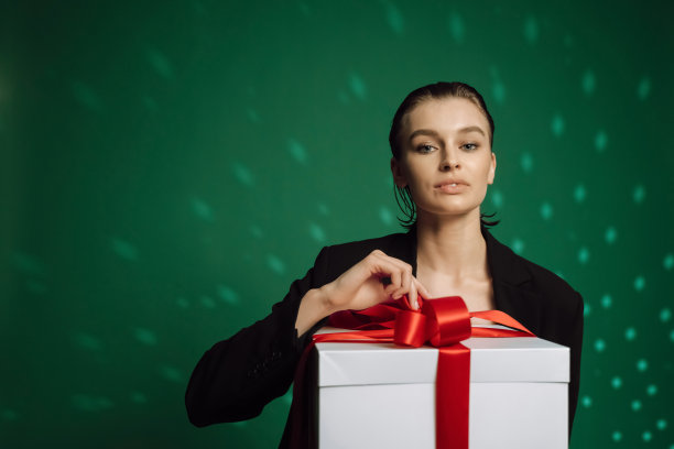 礼物,礼物。快乐的白人女士拿着包装盒，感觉兴奋的绿色工作室背景。可爱的金发模特收到节日惊喜，庆祝妇女节图片下载