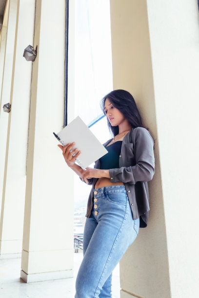 美丽的拉丁青少年学生与笔记本，书，阅读和学习靠在墙上图片下载