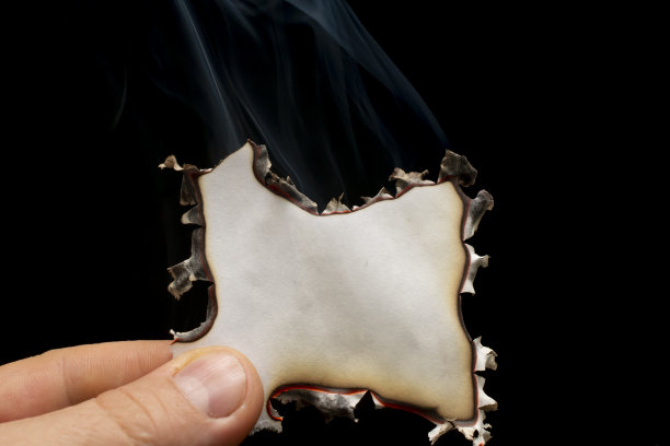 燃烧的纸边在手里，发光的纸边在黑色的背景图片下载