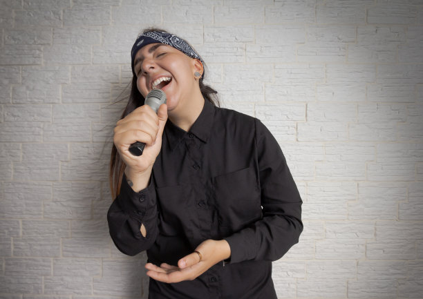 一个女人拿着麦克风唱卡拉ok。图片下载