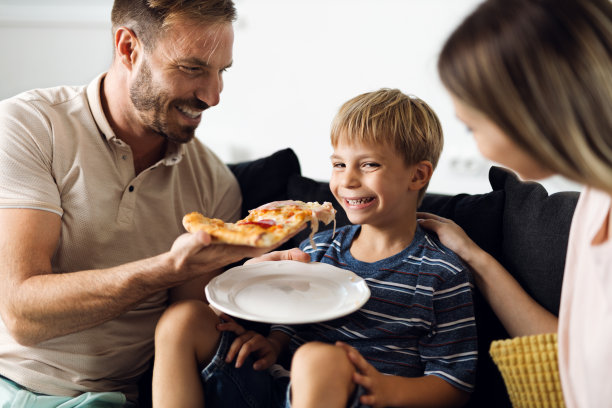 中年父亲在家给儿子吃披萨图片下载