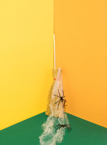 最小的万圣节场景与扫帚，蜘蛛网和蜘蛛在黄色和深绿色的背景。令人毛骨悚然的节日概念。图片下载