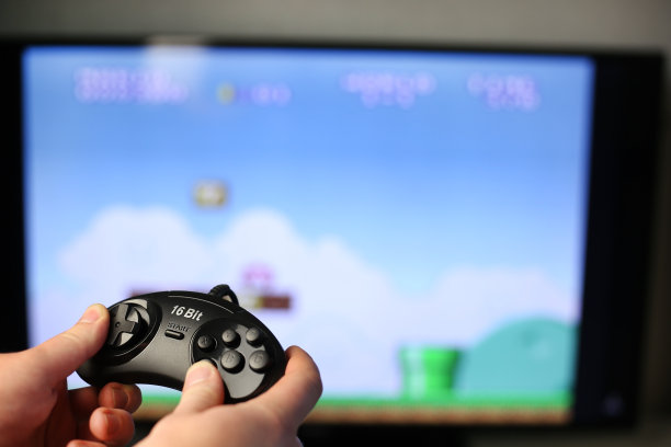 拿着经典的黑色操纵杆在电视上玩复古游戏图片下载