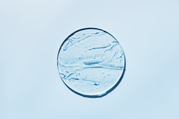 凝胶化妆品样品在培养皿中，蓝色背景，硬阴影。抽象的科学、医学和美的概念图片下载