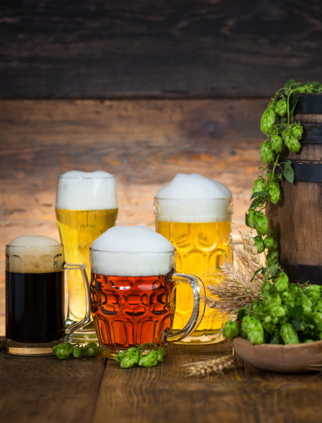 木桌上的玻璃杯里装着不同的淡啤酒和黑啤酒图片下载