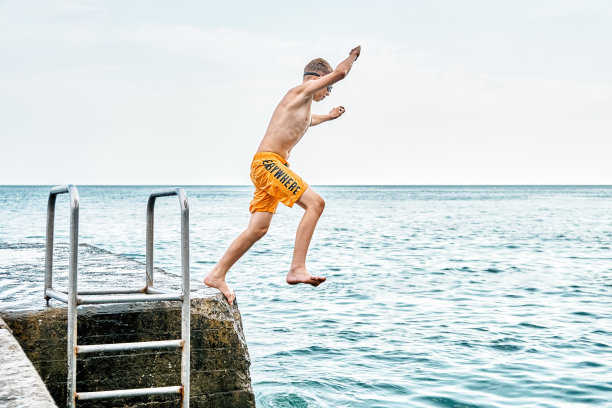 小男孩从码头跳到海里耍把戏的瞬间图片下载