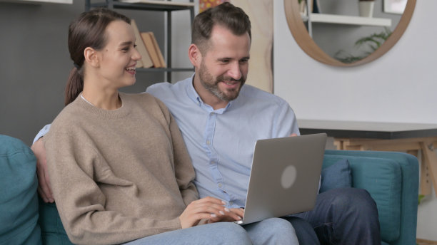 一对情侣坐在沙发上用笔记本电脑庆祝成功图片下载