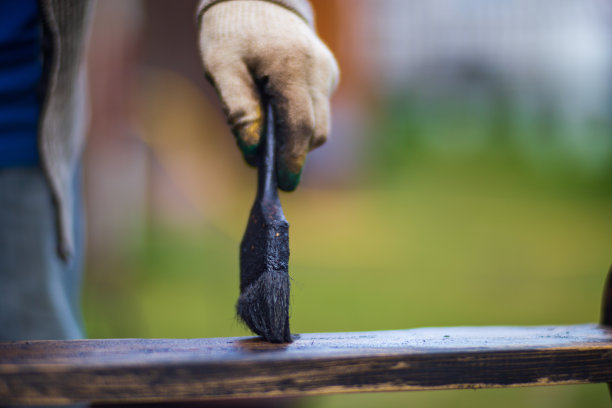 一个人用刷子把颜料涂在木头表面。漆工作图片下载