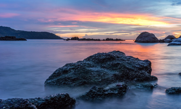 海滩上五颜六色的日落，水中的石头海景图片下载