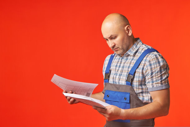 一个穿着工作套装的秃头男子站在那里，查看他手中的文件图片下载