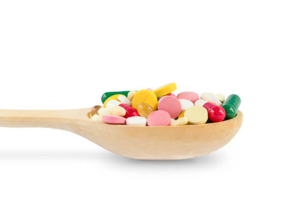 在白色的背景上有一个装有各种药丸的木勺图片下载