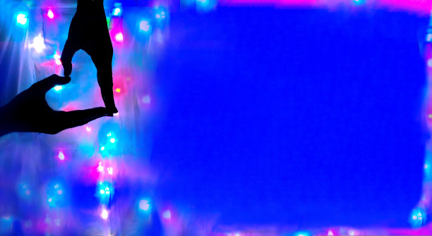 双手的剪影以心形的形式叠放在不对焦的多色灯光和蓝色背景上，复制空间。爱的概念图片下载