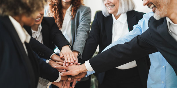 不同种族的商务人士在现代办公室里一起叠手庆祝图片下载