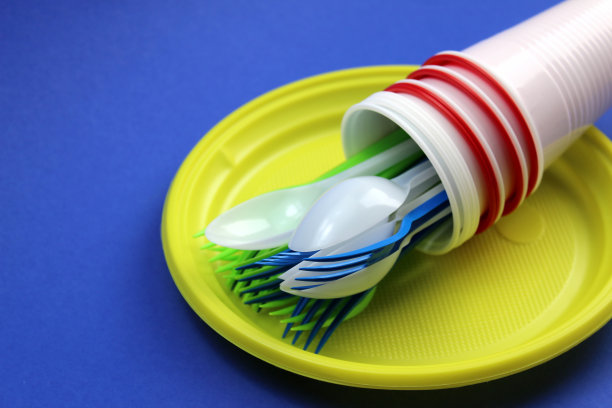 一次性餐具堆在蓝色的背景上。图片下载