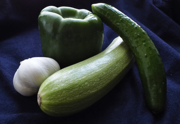 绿色甜椒，黄瓜，西葫芦和大蒜在蓝色的背景图片下载
