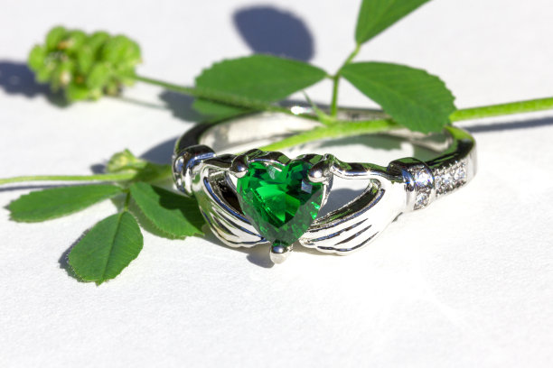 克拉达戒指与绿色祖母绿。传统的爱尔兰戒指，双手握着一颗心型绿色宝石的形状。图片下载