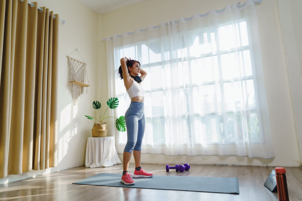 在线科技平板电脑在家进行健身课程，穿着运动服和运动鞋的亚洲女性在室内锻炼燃烧脂肪，在瑜伽垫上锻炼身体，在家健康的生活方式。图片下载