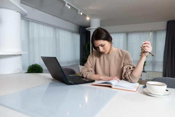 年轻的大学生在家里用笔记本电脑做作业。女孩在电脑上阅读和做关于堕胎的学校项目的研究。图片下载