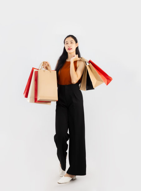 漂亮的亚洲女人长头发携带和持有红色和棕色的纸购物摆姿势行走与身体在白色的背景。图片下载