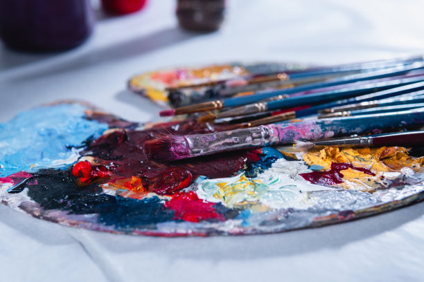 高质量的摄影。靠近一个染色的调色板和磨损的画笔。各种大小不同的磨损刷子。图片下载