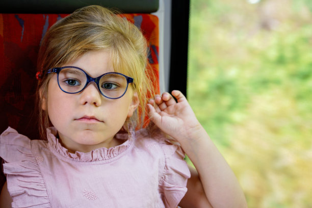 学龄前的小女孩戴着眼镜坐在火车上，一边移动一边看着窗外。快乐的孩子，微笑的孩子乘坐火车和家人一起度假或者周末旅行。图片下载