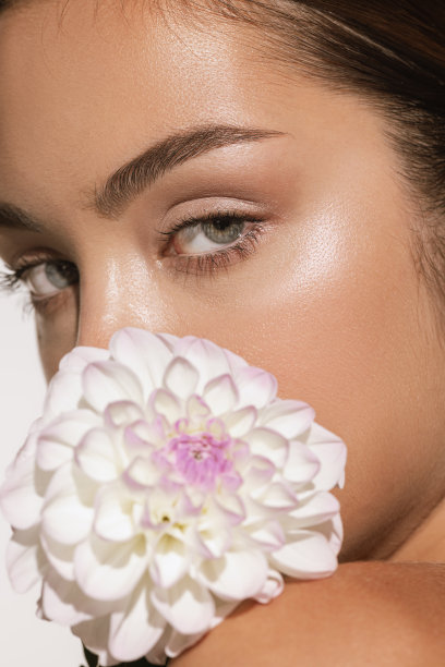 美丽的肖像迷人的年轻女孩与花孤立在白色的工作室背景。化妆品、自然美和美学美容理念。图片下载
