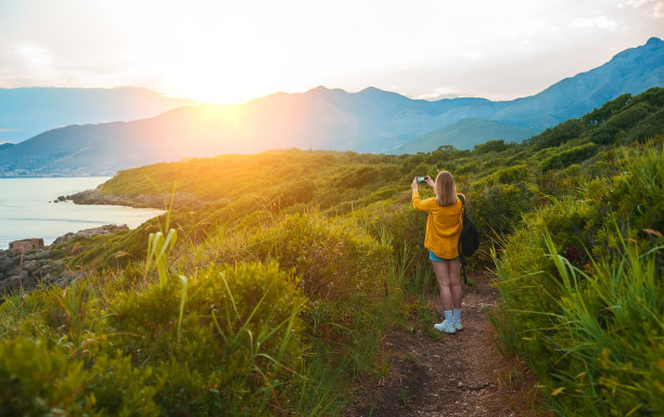 女人与背包照片的山在日落。图片下载