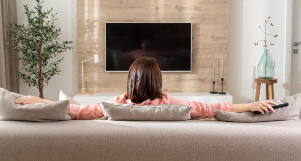 女孩在客厅的沙发上，电视机前摆出沉思的姿势图片下载