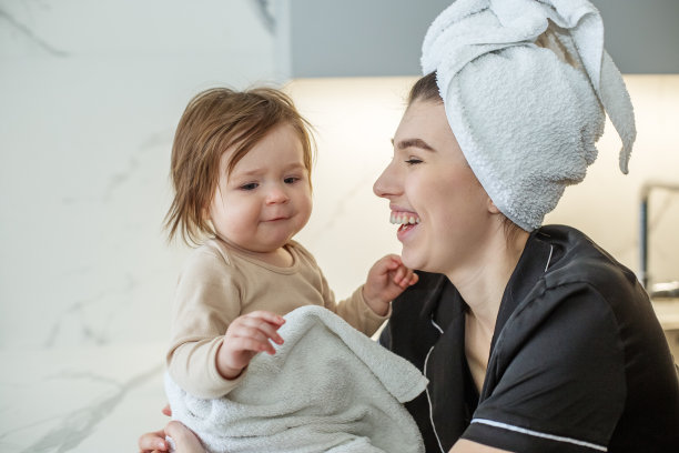 美丽的年轻母亲是有乐趣的婴儿蹒跚学步的女孩。保健和母亲。图片下载
