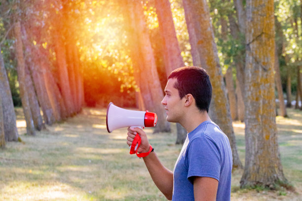 十几岁的男孩手拿扩音器站在田野中央图片下载