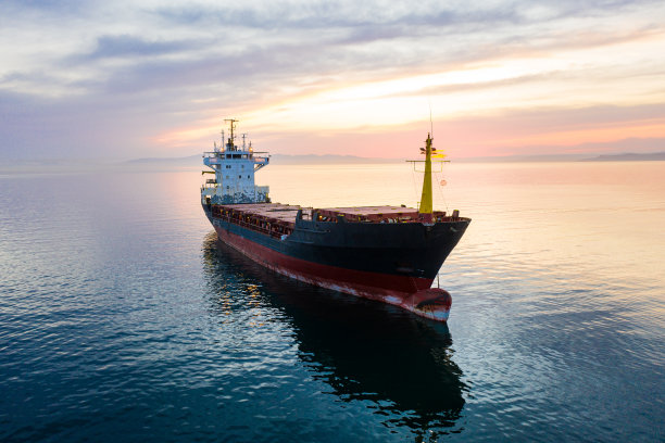 散装货船停泊在橙色日落，鸟瞰图。彩色的天空图片下载