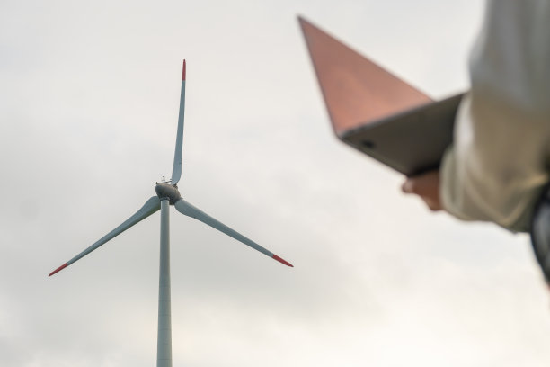 特写的女人用一台笔记本电脑在灰色的天空下控制风车的工作图片下载