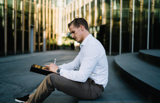 白种商人使用现代触摸板浏览金融交易通知网站的侧面视图，聪明的休闲员工使用触摸板进行网页交流图片下载