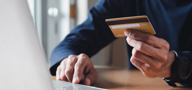 男人手里拿着信用卡，在家里使用笔记本电脑，商人或企业家工作，网上购物，电子商务，网上银行，消费的概念。图片下载