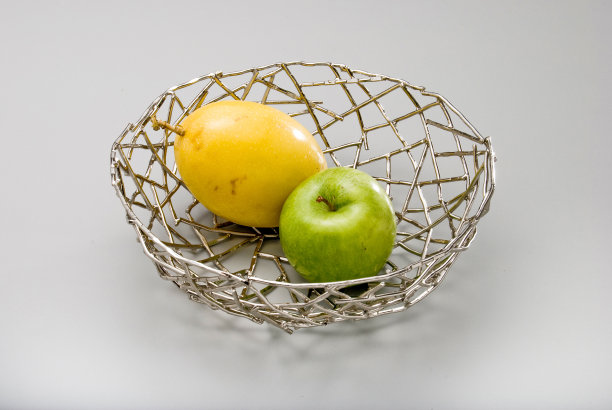 现代金属水果篮与切割，一个百香果和一个青苹果内，孤立在白色图片下载